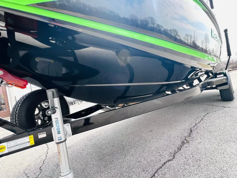 Slide: The Image of 2015 MasterCraft X25 boat on trailer, showcasing sleek hull design and vibrant green accents. - 49