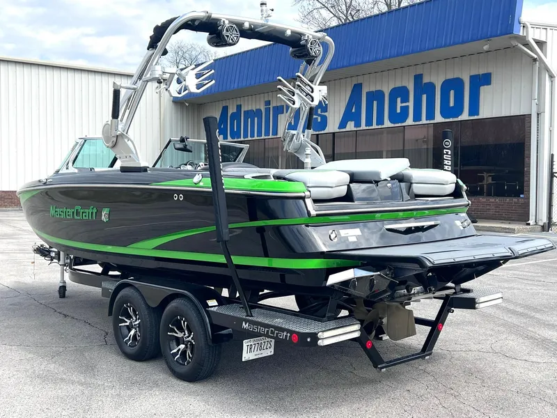 Slide: The Image of 2015 MasterCraft X25 boat with green accents on a trailer outside a building. - 5