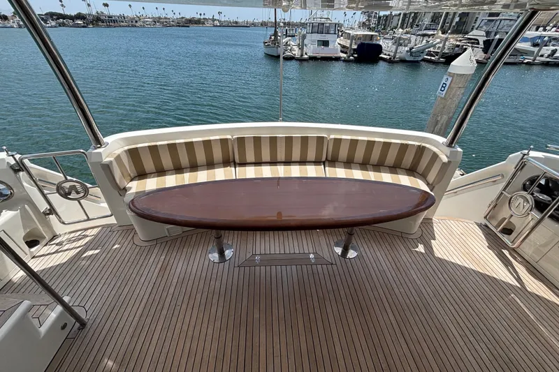 Slide: The Image of Luxurious 2010 Norseman 80 yacht deck with striped seating and oval table, overlooking marina. - 127