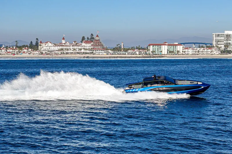 Slide: The Image of 2023 Tecnomar Lamborghini 63 yacht speeding on ocean near coastal cityscape. - 0