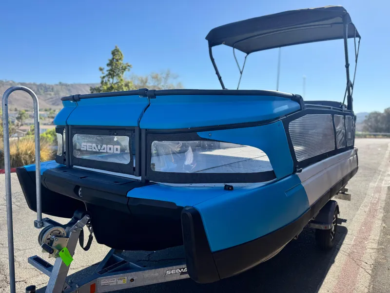 Slide: The Image of 2023 Sea-Doo Switch Cruise 21 pontoon boat on trailer, blue exterior, sunny day. - 4