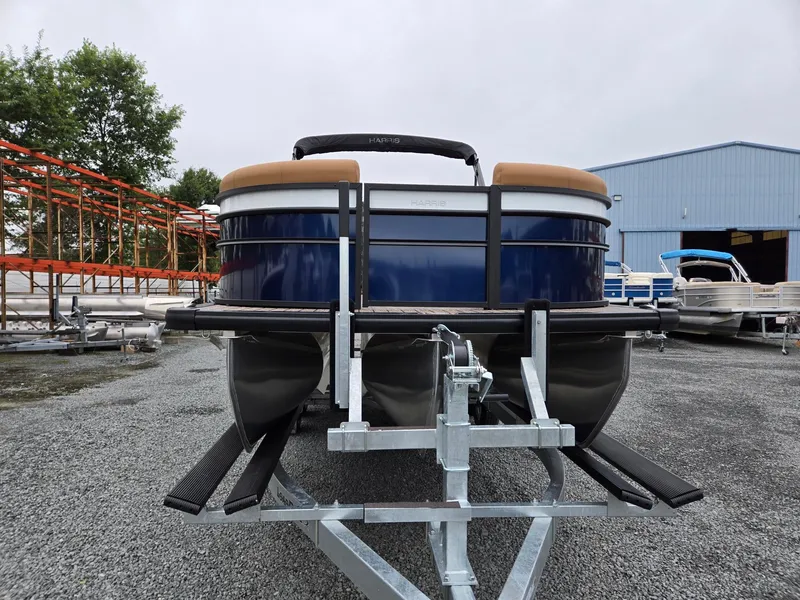 Slide: The Image of 2026 Harris Cruiser 210 pontoon boat on trailer, parked outdoors near a blue building. - 10