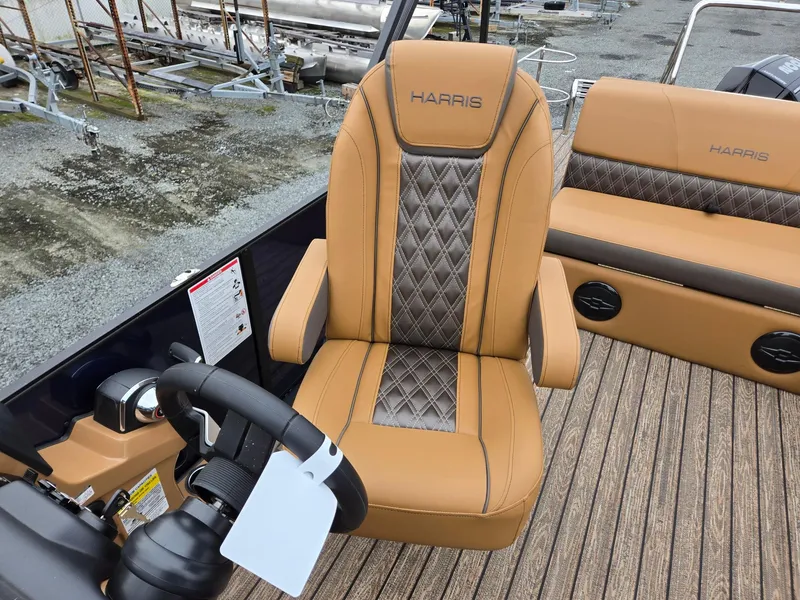Slide: The Image of 2026 Harris Cruiser 210 boat interior with tan and gray seating, steering wheel, and controls. - 16