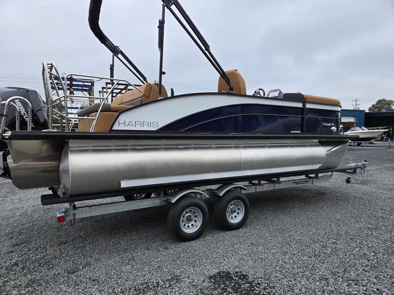 Slide: The Image of 2026 Harris Cruiser 210 pontoon boat on a trailer, parked on gravel. - 6