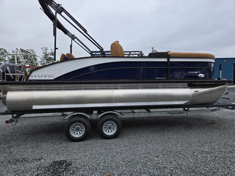 Slide: The Image of 2026 Harris Cruiser 210 pontoon boat on a trailer, parked on gravel. - 7