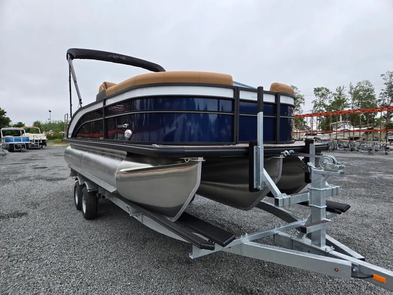 Slide: The Image of 2026 Harris Cruiser 210 pontoon boat on trailer, parked on gravel lot. - 9