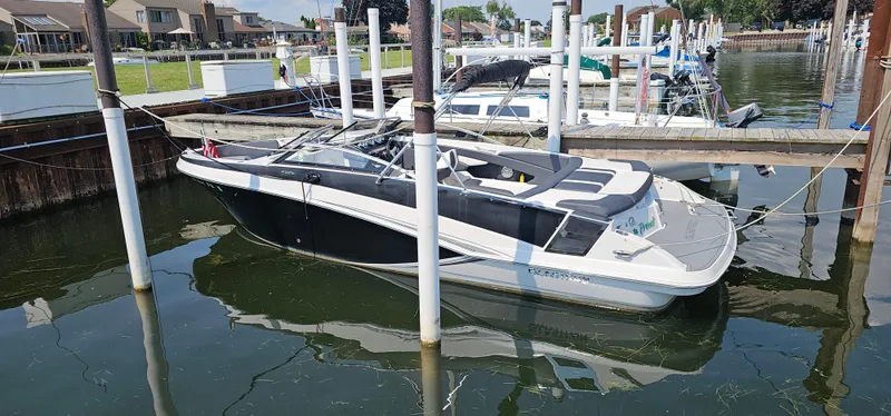 The Image of 2014 Glastron GT 245 boat docked in a marina, featuring sleek black and white design. - 0
