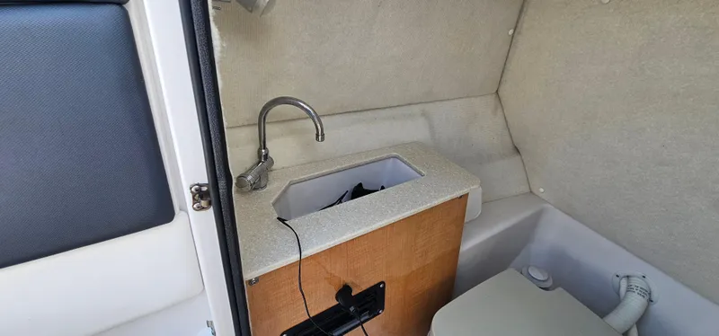 Slide: The Image of 2014 Glastron GT 245 boat interior with sink and compact toilet. - 12