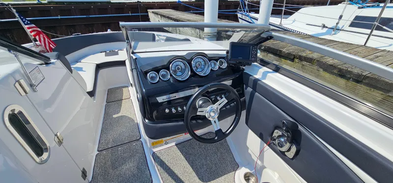 Slide: The Image of 2014 Glastron GT 245 boat cockpit with steering wheel, gauges, and navigation system. - 14