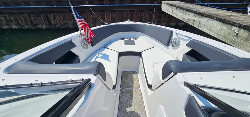 Slide: The Image of 2014 Glastron GT 245 boat interior with seating, American flag, docked by wooden pier. - 17