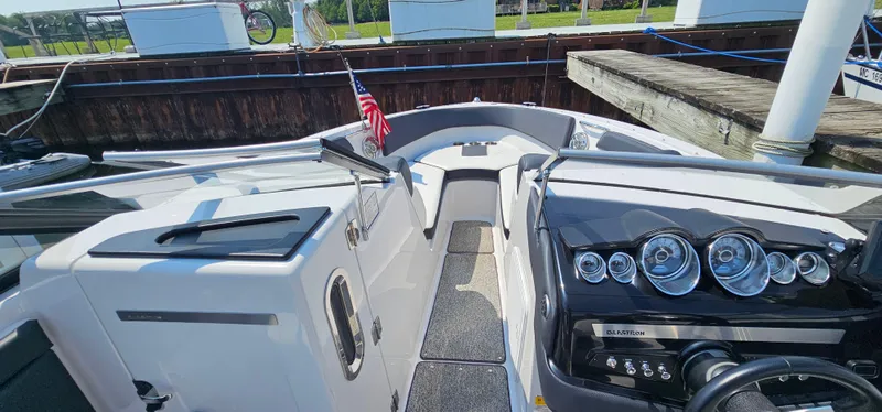 Slide: The Image of 2014 Glastron GT 245 boat interior with dashboard and American flag at dock. - 18