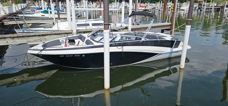 Slide: The Image of 2014 Glastron GT 245 boat docked in a marina, featuring sleek black and white design. - 2