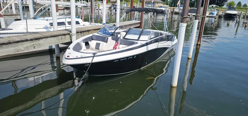 Slide: The Image of 2014 Glastron GT 245 boat docked in a marina, featuring sleek black and white design. - 3