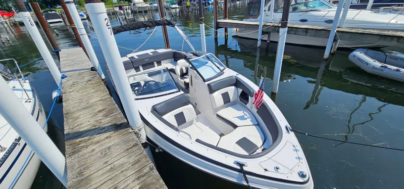 Slide: The Image of 2014 Glastron GT 245 boat docked at marina, featuring sleek design and spacious seating. - 4