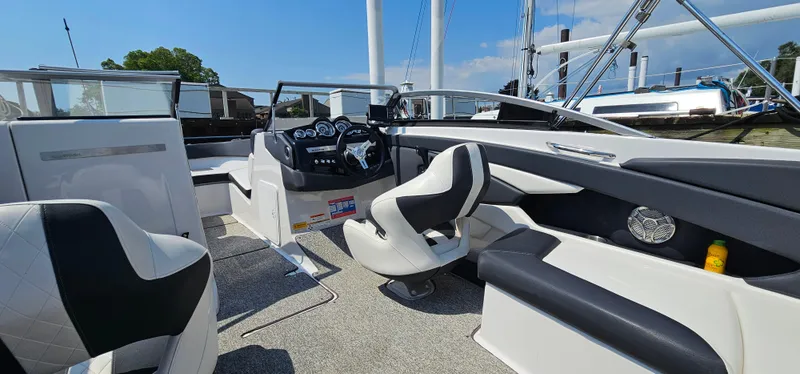 Slide: The Image of 2014 Glastron GT 245 boat interior with modern dashboard and seating, docked under clear skies. - 8