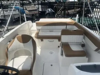 Slide: The Image of 2022 Bayliner VR6 boat interior with white and brown seating, docked near a fence. - 10