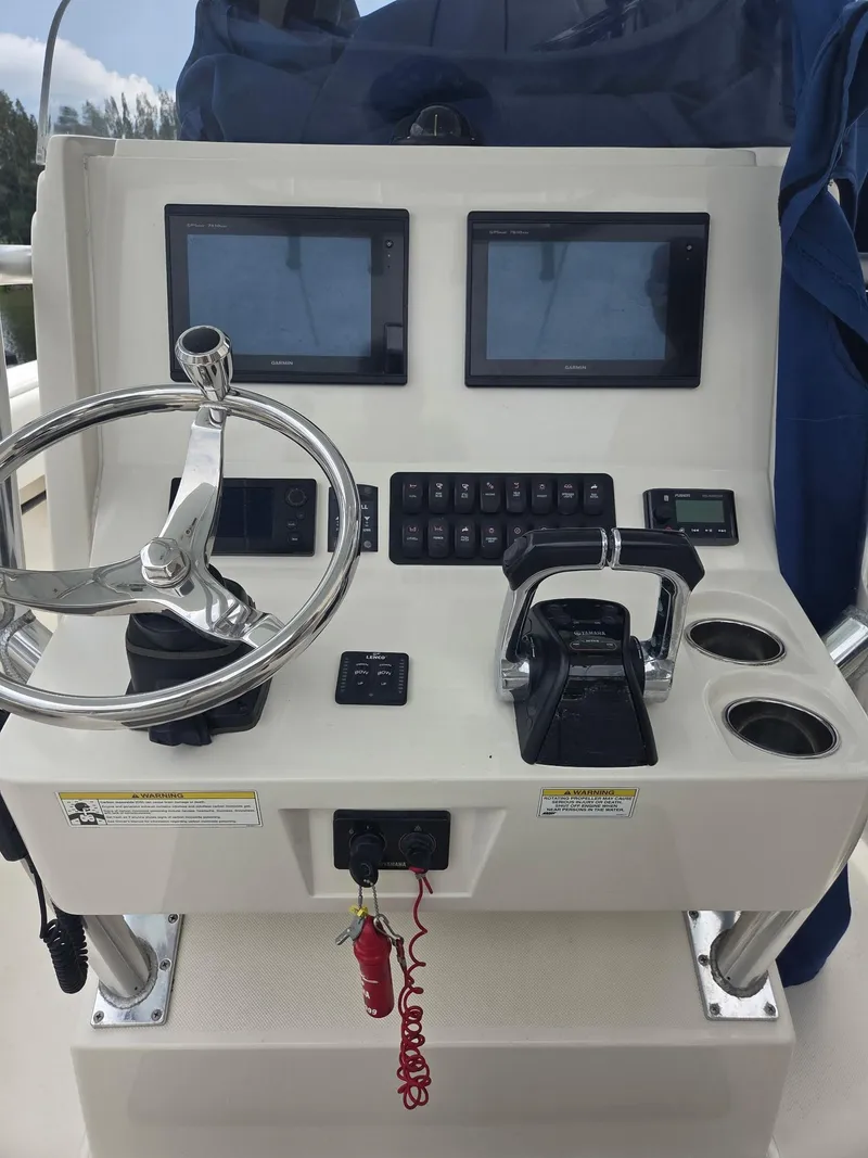 Slide: The Image of Control panel of a 2015 Jupiter 26 FS boat with steering wheel and dual screens. - 10
