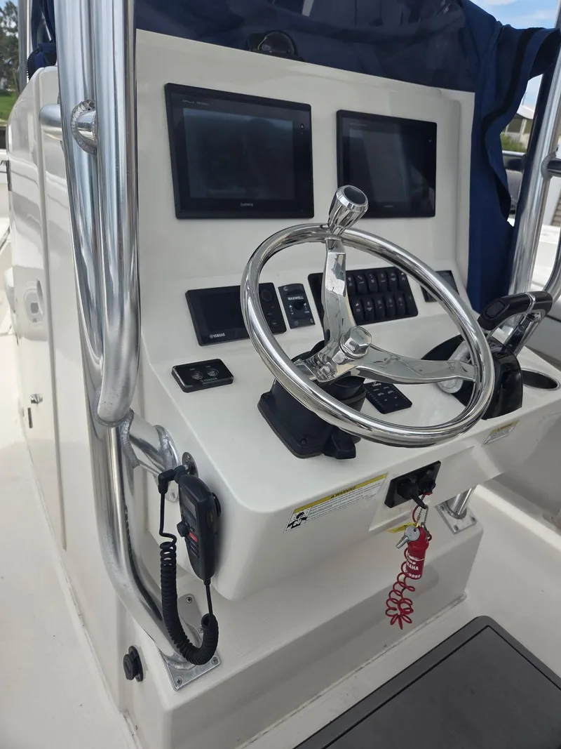 Slide: The Image of Control console of a 2015 Jupiter 26 FS boat with steering wheel and navigation screens. - 11