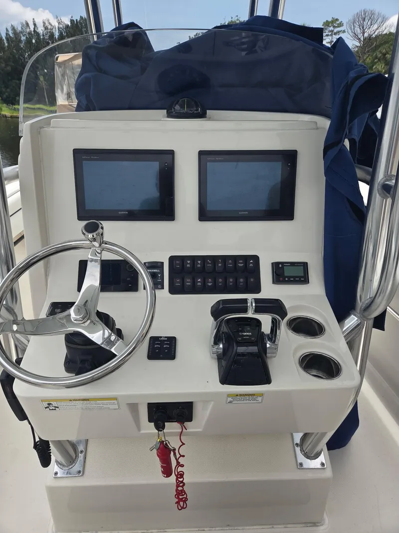 Slide: The Image of Control panel of a 2015 Jupiter 26 FS boat with dual screens and steering wheel. - 15