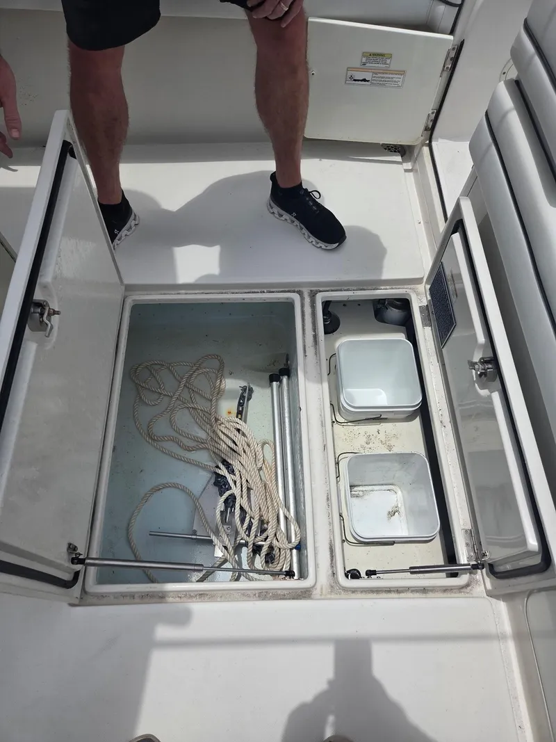 Slide: The Image of Open storage compartments on a 2015 Jupiter 26 FS boat deck with ropes and containers. - 19