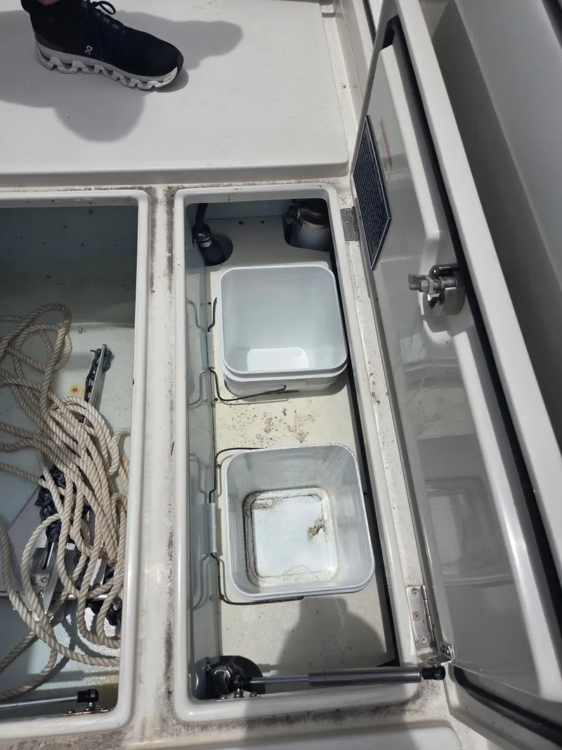 Slide: The Image of Open storage compartments on a 2015 Jupiter 26 FS boat, featuring ropes and containers. - 28