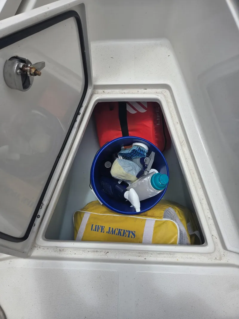Slide: The Image of Open storage compartment on 2015 Jupiter 26 FS boat with life jackets and cleaning supplies. - 33