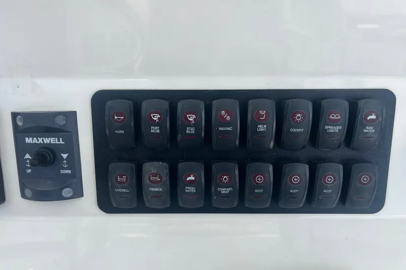 Slide: The Image of Control panel of a 2015 Jupiter 26 FS boat with various switches and Maxwell anchor control. - 54