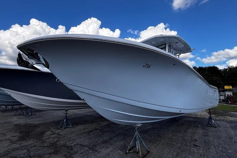 The Image of 2026 Tidewater 256 CC Adventure boat on stands under a blue sky with clouds. - 1