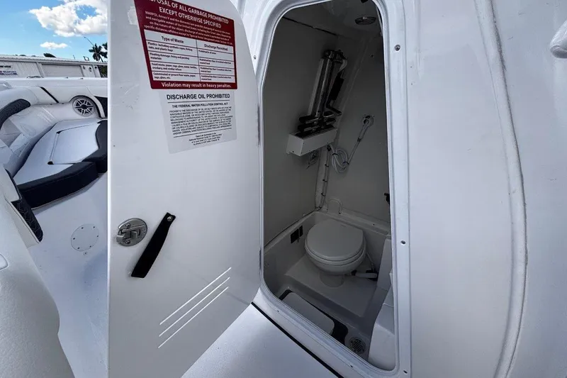 Slide: The Image of 2026 Tidewater 256 CC Adventure boat interior with open door revealing compact marine toilet. - 28