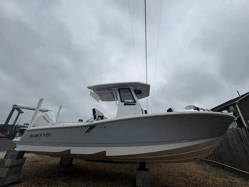 The Image of 2026 Blackfin 242HB boat on blocks under cloudy sky. - 1