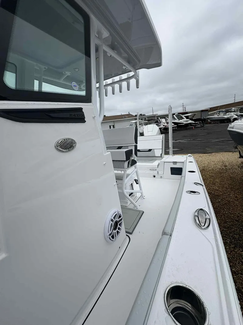 Slide: The Image of 2026 Blackfin 242HB boat, side view, showcasing deck and seating area in a marina setting. - 12