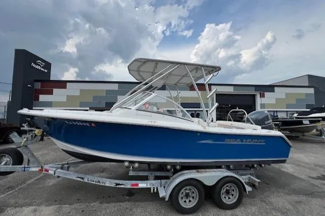 Slide: The Image of 2013 Sea Hunt Escape 211 LE boat on trailer, parked outdoors under cloudy sky. - 1