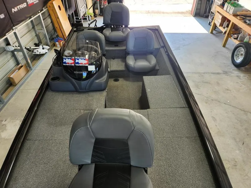 Slide: The Image of 2024 Tracker Pro 170 boat interior with gray seating and carpeted deck in a garage. - 9