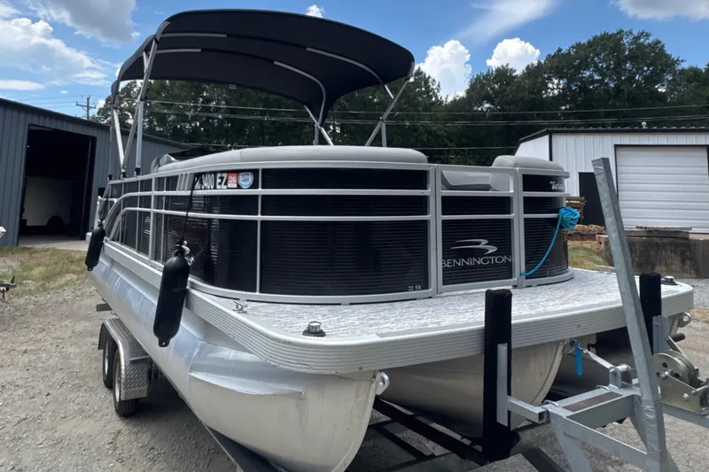 Slide: The Image of 2023 Bennington 22SX Swingback pontoon boat on trailer, parked outdoors. - 10