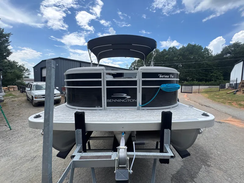 Slide: The Image of 2023 Bennington 22SX Swingback pontoon boat on trailer, parked outdoors under blue sky. - 11
