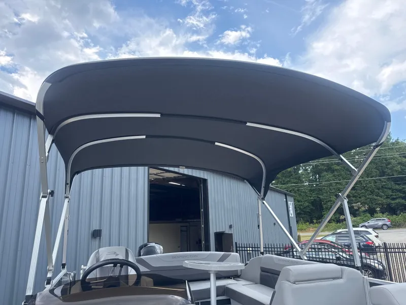 Slide: The Image of 2023 Bennington 22SX SWINGBACK pontoon boat with canopy, parked outdoors. - 18