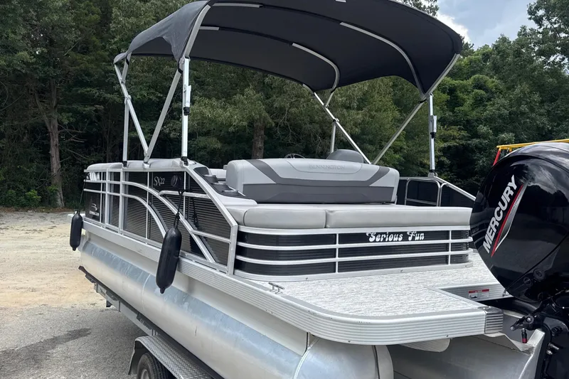 Slide: The Image of 2023 Bennington 22SX Swingback pontoon boat with Mercury engine, parked outdoors. - 4
