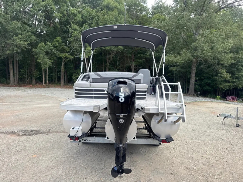 Slide: The Image of 2023 Bennington 22SX Swingback pontoon boat with outboard motor, parked on gravel. - 6