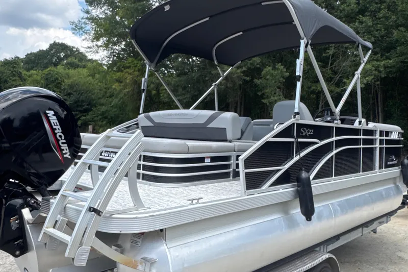 Slide: The Image of 2023 Bennington 22SX Swingback pontoon boat with Mercury engine and canopy, parked outdoors. - 7