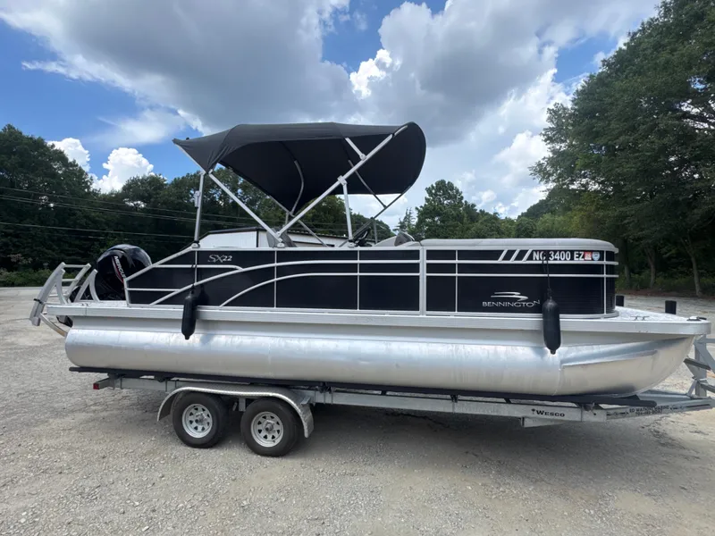 Slide: The Image of 2023 Bennington 22SX SWINGBACK pontoon boat on trailer under cloudy sky. - 9