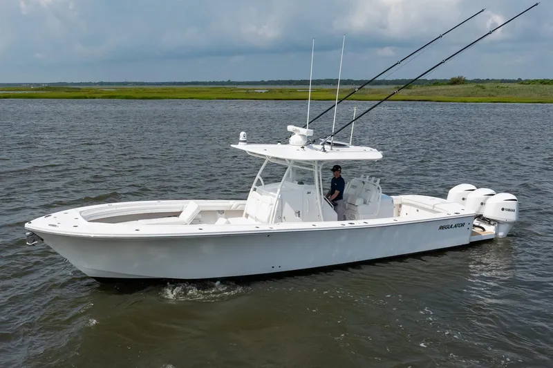 Slide: The Image of 2019 Regulator 34 Center Console boat on water with fishing rods and Yamaha engines. - 2
