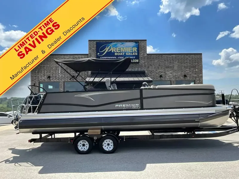 The Image of A gray pontoon boat on a trailer in front of a building with a promotional banner. - 1