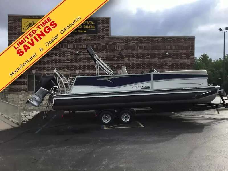 The Image of A Premier 250 SunSation RL pontoon boat on a trailer in front of a brick building. - 1
