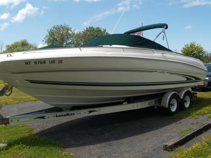 Slide: The Image of 2001 Sea Ray 260 Bow Rider Select on trailer, parked outdoors under blue sky. - 2