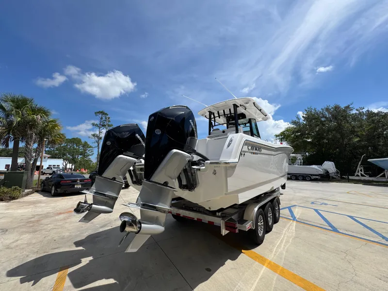 Slide: The Image of 2026 Caymas 30 CT boat with dual outboard motors on a trailer under a clear blue sky. - 12
