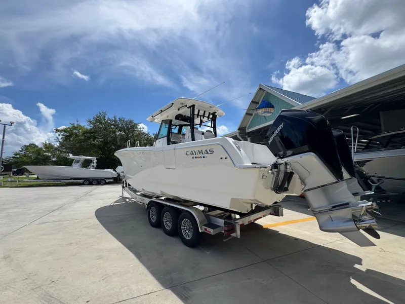Slide: The Image of 2026 Caymas 30 CT boat on trailer, parked outdoors under a partly cloudy sky. - 16