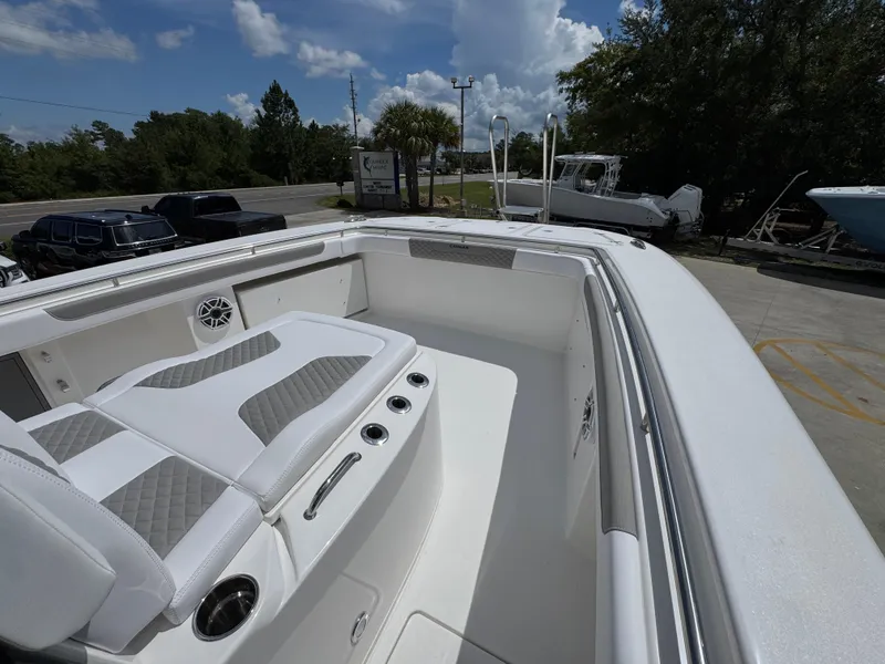 Slide: The Image of 2026 Caymas 30 CT boat interior with white seating and cup holders, parked outdoors. - 22