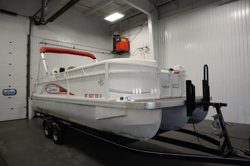 Slide: The Image of 2014 JC 22 Limited pontoon boat with red canopy in indoor storage. - 2