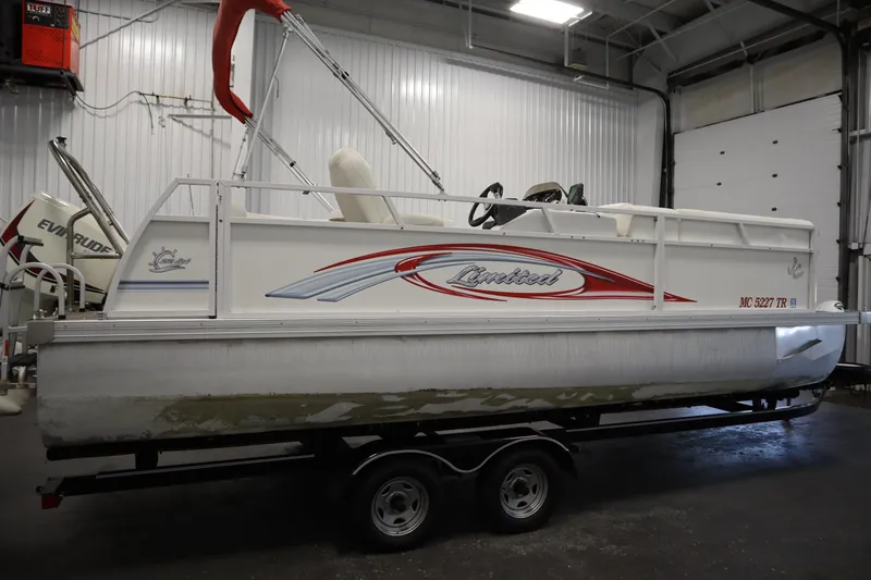 Slide: The Image of 2014 JC 22 Limited pontoon boat in a garage, featuring red and white design. - 3