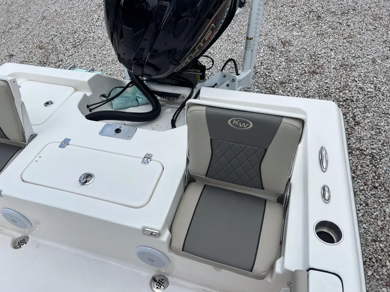 Slide: The Image of 2026 Key West 230 Bay Reef boat interior with seating and motor, on gravel surface. - 17